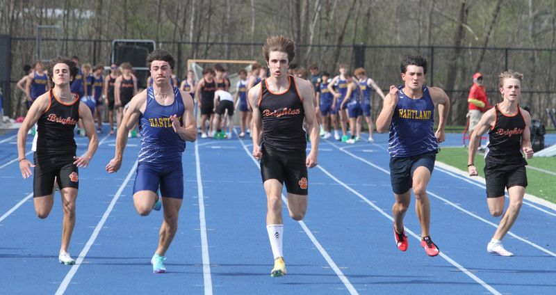 Brighton's Mason Gay (center) wins the 100-meter dash during a track and field meet against Hartland on Tuesday, April 21, 2026.