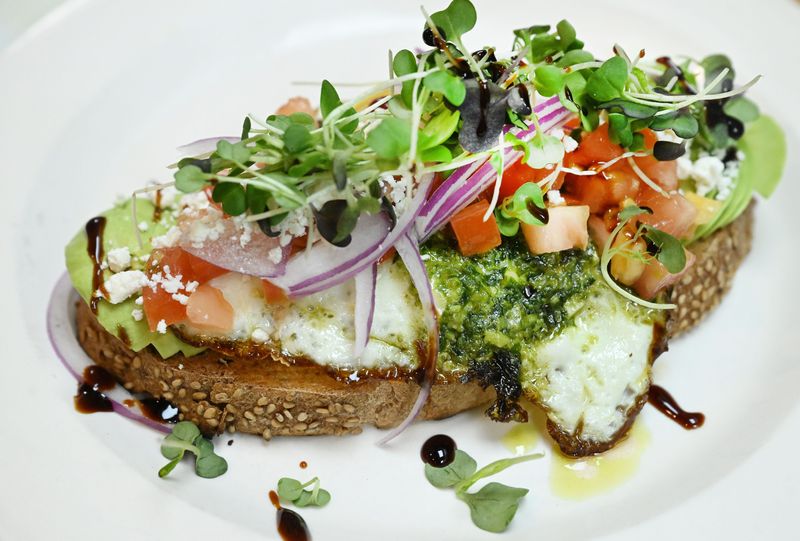 Avocado and feta toast consisting of pesto sunny side up egg, feta cheese, tomato, red onion, balsamic glaze and micro greens at Ellen's Bakery & Cafe, a bakery and restaurant in Sylvan Lake, Michigan on April 22, 2026.