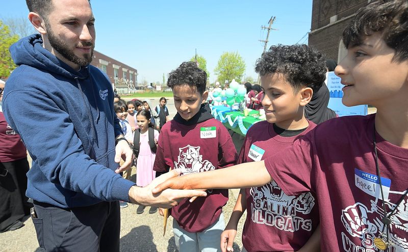 Dearborn mayor Abdullah Hammond shakes hands with Salina school students Noah Ali, 12, Nawar Ali, 12 and Aqeel Ahmed, 12 as they talk to him on various conservation efforts during Earth Day activities in Dearborn, Michigan on April 22, 2026.