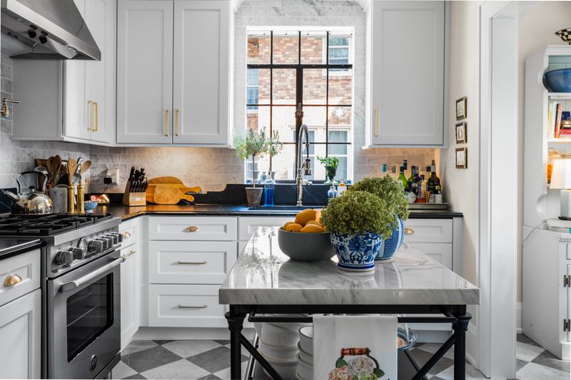 The couple upgraded the kitchen without changing the floor plan, moving the refrigerator, centering the stove and adding white cabinets and soapstone countertops. “I love black and white in the kitchen,” the designer says. “It’s so classic.” A marble-top baker’s table from Wayfair serves as a handy island in the small space.