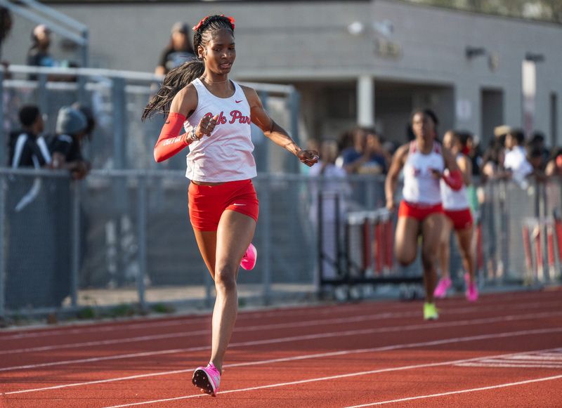 Oak Park High School sprinter Navaeh Burns, center, competes in a 400-meter race during a track meet at her school in Oak Park on Thursday, April 23, 2026. Burns, who is currently a junior, has won six state titles across her first two years of high school and is looking to pick up 3 more again as a junior.