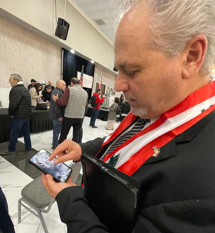 Wayne County Commissioner Sam Baydoun, D-Dearborn, shows an image on his phone of the destruction in his hometown of Bint Jbeil, Lebanon, zooming in on the elementary school he once attended and his father's home, which he said was destroyed in Israeli attacks in 2026. Baydoun is seen here at the Bint Jebail Cultural Center in Dearborn.