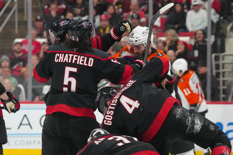 Philadelphia Flyers center Sean Couturier (14) battle Carolina Hurricanes defenseman Shayne Gostisbehere (4) and defenseman Jalen Chatfield (5) during the second period at Lenovo Center.