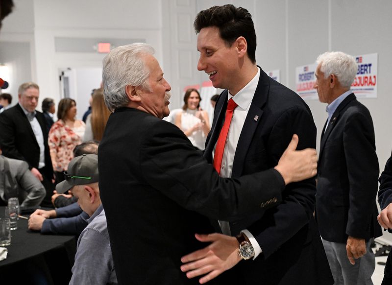 Robert Lulgjuraj, Republican candidate for U.S. Congress Dist. 10, right, hugs supporter Fr. Fred Kalaj during Lulgjuraj’s campaign event on May 4, 2026 at Palazzo Grande in Shelby Township, Mich.