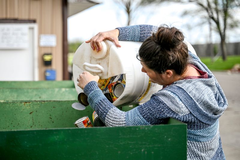Laura Kresge, of Maple Rapids, throws cans into bins at the St. Johns Recycling Center on Wednesday, May 6, 2026, in St. Johns.