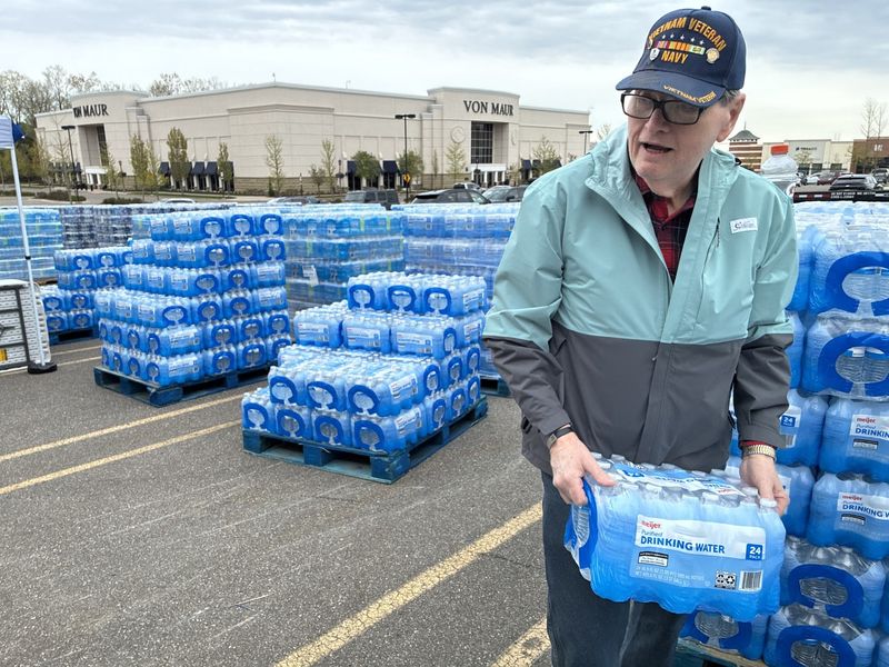 Jim Jensen, 75, grabs a case of water bottles to load into a vehicle on Tuesday, May 12, 2026, at a water supply site at The Village of Rochester Hills parking lot.