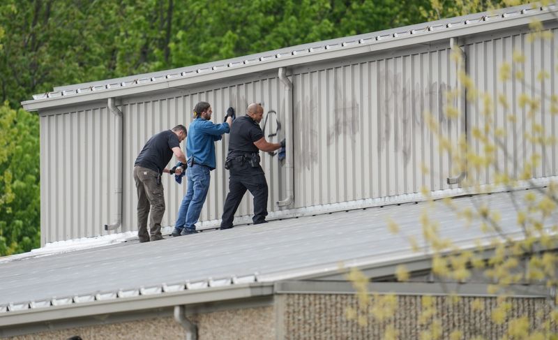 Workers clean off paint from vandalism above the entrance of Lansing Christian School, Friday, May 15, 2026.