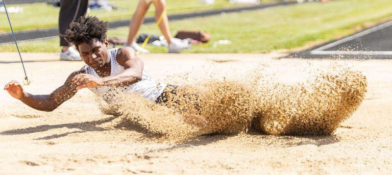 West Ottawa's Christian Lewis finishes a long jump at the Division 1 track and field regional on Friday, May 15, at Zeeland Stadium.
