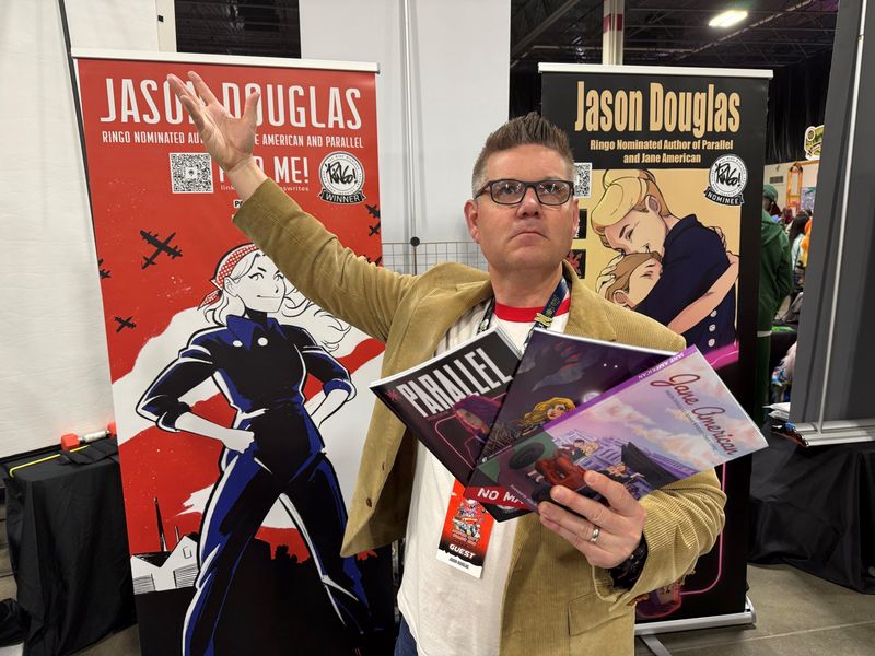 Jason Douglas poses with his graphic novels May 16, 2026, at the Motor City Comic Con in Novi.