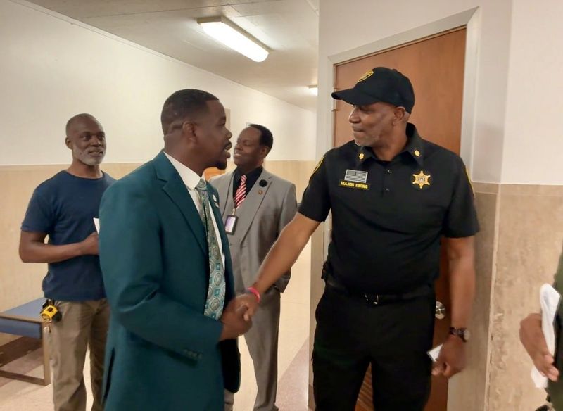 Pontiac City Council President Adrian Austin, left, shakes Oakland County Sheriff Maj. Andre Ewing's hand on Tuesday, May 19, 2026, during a council meeting at city hall.