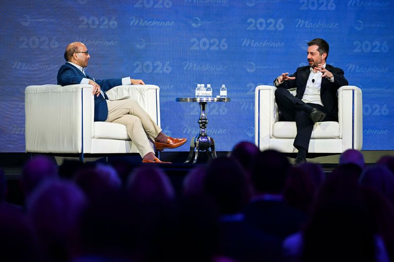 Former U.S. Transporation Secretary Pete Buttigieg, right, chats with Detroit Regional Chamber CEO Sandy Baruah, left, about the status of the Gordie Howe International Bridge during the Mackinac Policy  Conference on Wednesday, May 27, 2026, at the Grand Hotel on Mackinac Island.