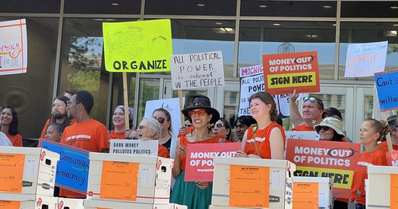 Supporters of the Michiganders for Money Out of Politics campaign gather outside the Secretary of State's Lansing headquarters on Wednesday, May 27, 2026.