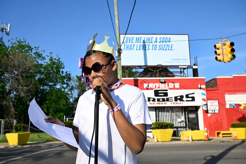 Gabrielle Walk, who attends the Cesar Chavez Academy in Detroit, reads a poem she wrote as a billboard behind her, located near the corner of E. Forest street and Cadillac Boulevard in Detroit, displays one of her poem’s verses on Wednesday, May 27, 2026.