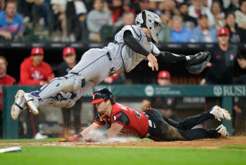 Andrew Benintendi #23 of the White Sox dives under Dillion Dingler #13 of the Tigers to tie the game in the bottom of the ninth inning at Rate Field.