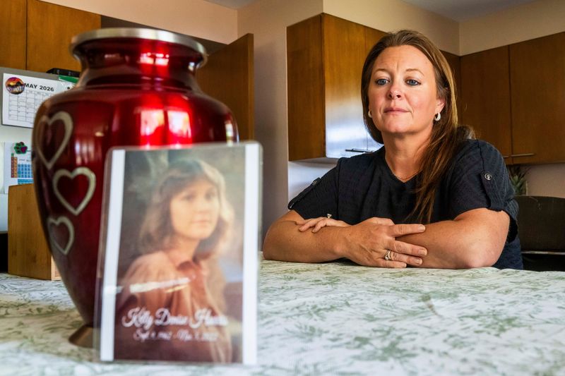 Patricia Collins, 40, sits alongside a photograph of her late mother, Kelly Harris, and an urn containing her remains on May 28, 2026 at her home in Mesick, Mich. Harris died in 2022, at age 60, less than a week after moving into the Pleasant Lake Lodge adult foster care facility in Cadillac. Criminal charges were filed against a home administrator.