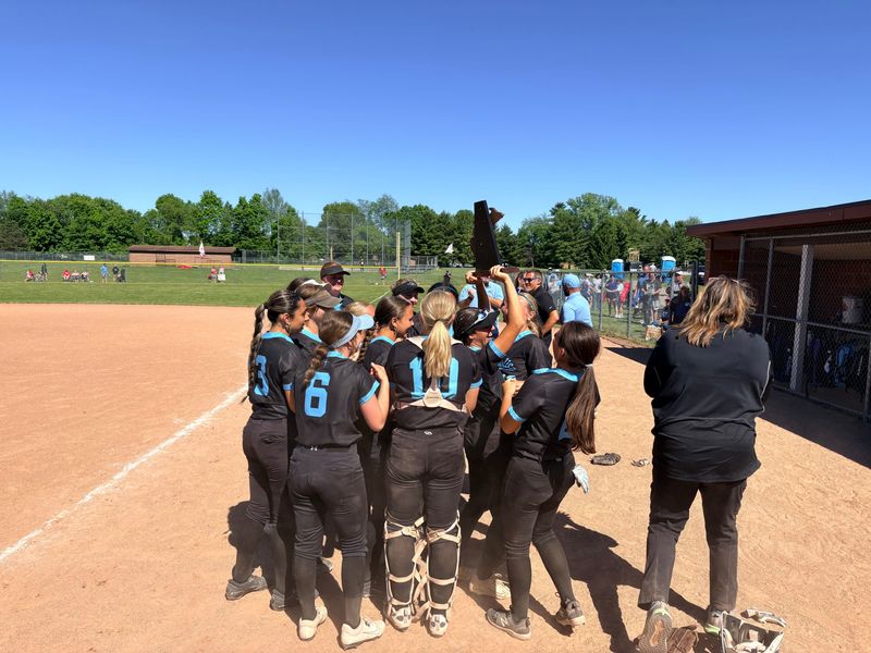 Lansing Catholic softball players celebrate with the district championship trophy after their 3-1 win over Laingsburg in a Division 3 district final Saturday, May 30, 2026 at Laingsburg High School.