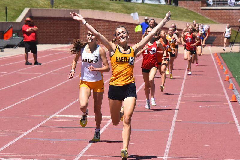 Hartland's Elliana Neuer throws her arms in the air after winning the 1,600-meter run during the state Division 1 track and field finals on Saturday, May 30, 2026 at Rockford High School.