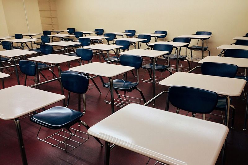 Empty desks are seen in a classroom.