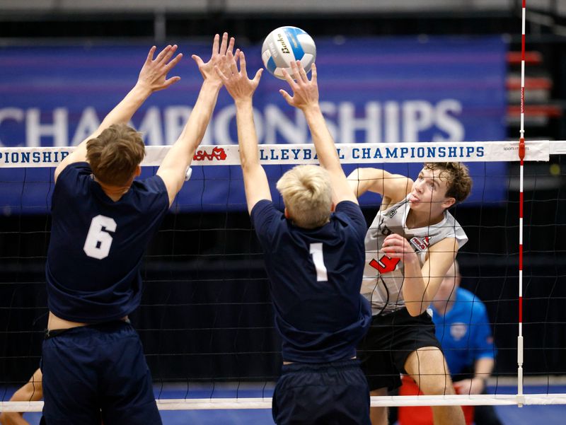 Lowell's Jaeger Smith, right, spikes against Grand Rapids Christian's Noah Jager, left, and Ezra Miller (1) during the Division 2 championship game on Saturday, June 6, 2026, in Battle Creek.