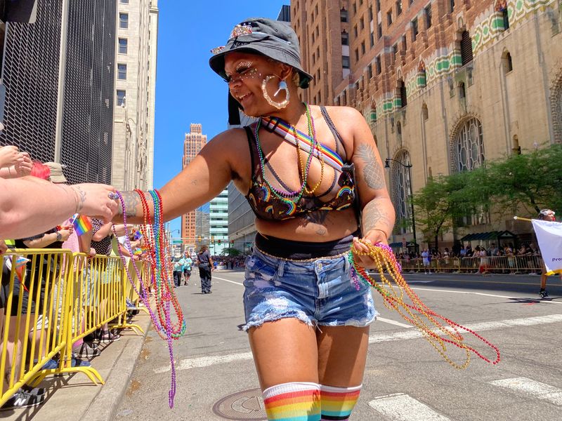 A marcher in the 2026 Motor City Pride parade breaks off to hand out multi-colored beads Sunday, June 7, 2026, in downtown Detroit.
