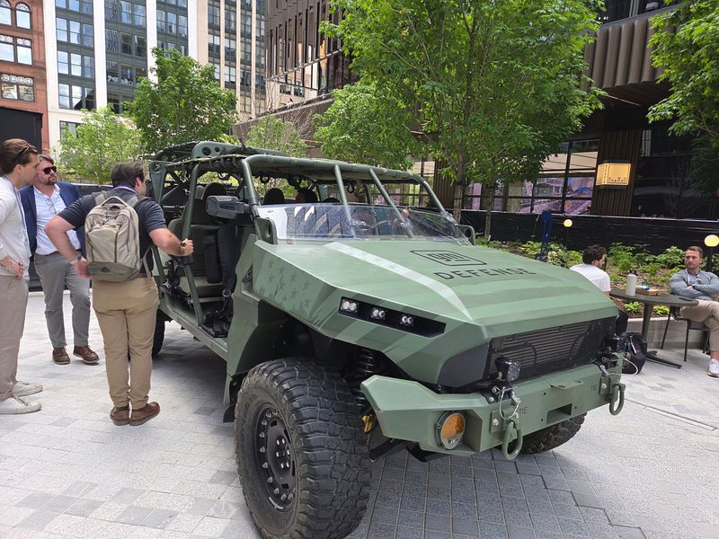 Attendees of the Reindustrialize defense, manufacturing and tech conference examine the Infantry Squad Vehicle Troop Carrier from General Motors Co. subsidiary GM Defense LLC on Tuesday, June 16, 2026 outside Hudson's Detroit downtown.