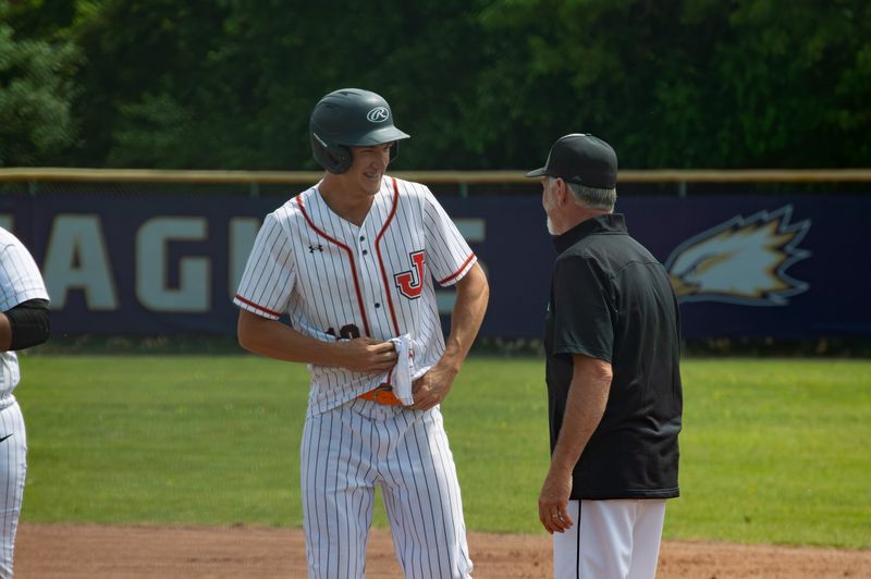 Senior Ian Doyle talks to coach Adair after getting on base in the regional title game.