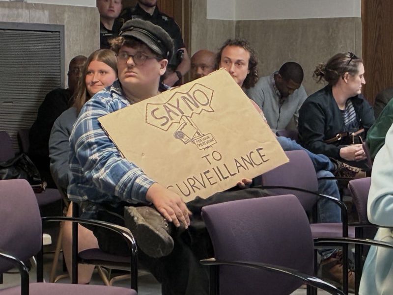 Daniel Van Leeuwen of Highland Park is seen with a sign in opposition to Flock Safety technology on Tuesday, June 16, 2026, at Pontiac City Hall.