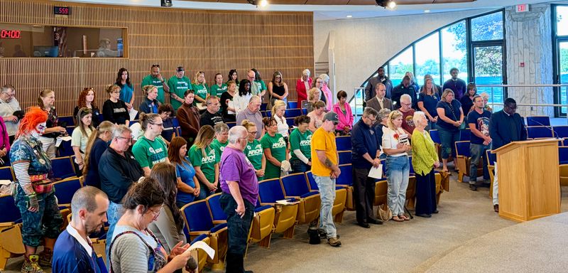 Members of AFSCME Michigan in green shirts and Teamsters Local 332 members stand among attendees during the Port Huron City Council meeting on June 22, 2026, at the Port Huron Municipal Office Center.