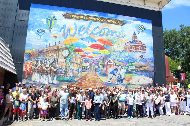 Community members pose for a photo before an expansive, colorful new mural in downtown Howell on June 23, 2026.