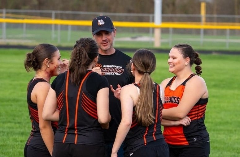 Coach Dave Raymond talks with members of Summerfield's girls track and field team.
