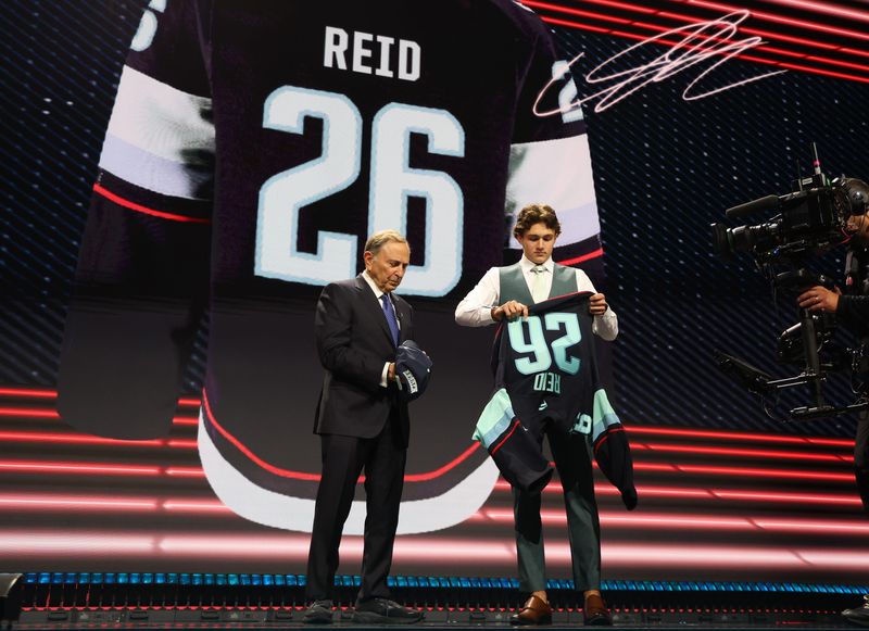 Chase Reid reacts beside NHL commissioner Gary Bettman after being selected with the seventh pick in the first round of the 2026 NHL Draft by the Seattle Kraken at KeyBank Center in Buffalo, New York, on Friday, June 26, 2026.
