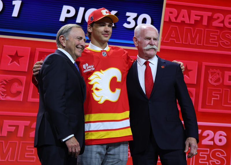 Jun 26, 2026; Buffalo, New York, USA; Jack Hextall reacts beside NHL commissioner Gary Bettman and former NHL player Lanny McDonald after being selected with the thirtieth pick in the first round of the 2026 NHL Draft by the Calgary Flames at KeyBank Center. Mandatory Credit: Timothy T. Ludwig-Imagn Images