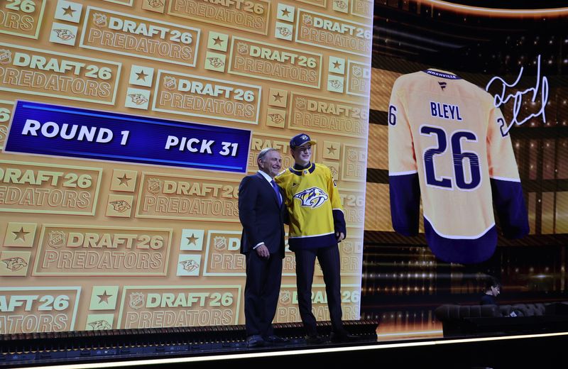 Jun 26, 2026; Buffalo, New York, USA; Tommy Bleyl reacts beside NHL commissioner Gary Bettman after being selected with the thirty first pick in the first round of the 2026 NHL Draft by the Nashville Predators at KeyBank Center. Mandatory Credit: Timothy T. Ludwig-Imagn Images