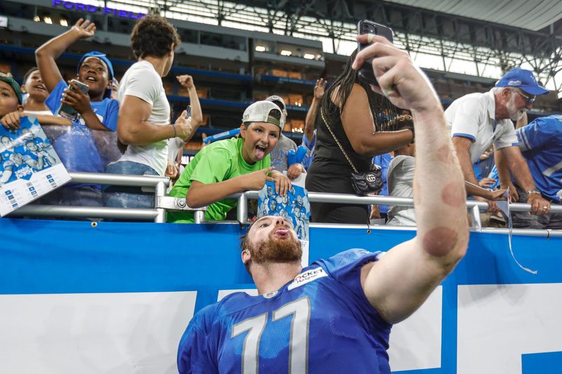 Detroit Lions center Frank Ragnow takes a selfie with fans after open practice at Family Fest at Ford Field in Detroit on Saturday, Aug. 6, 2022.