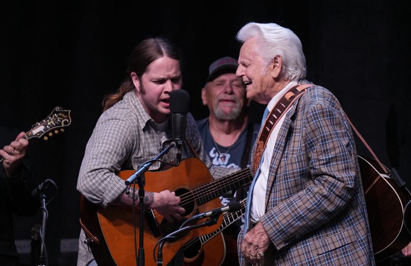 Billy Strings and bluegrass icon Del McCoury of the Del McCoury band sing Carter Stanley's "The Lonesome River," Friday, June 26, 2026, during the 54th Annual Charlotte Bluegrass Festival in Charlotte, Mich. Also pictured is Strings' father Terry Barber. [Matthew Dae Smith/USA Today Network]