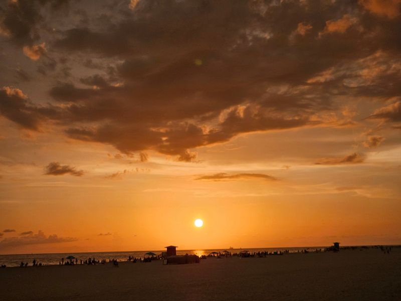 The sun sets over Lido Beach in Sarasota on June 27, 2026, as beachgoers gather along the Gulf shoreline.