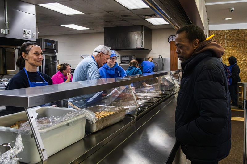 Workers and volunteers serve a meal at the East Side Food Kitchen.