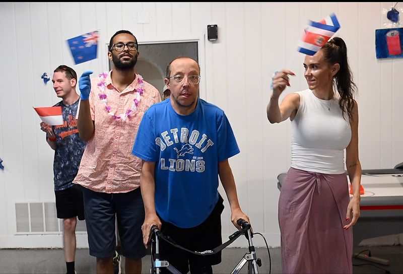 Jenny Brown, right, CEO of Dutton Farm, escorts Kenny Casbar during the opening of the Olympic games at Dutton Farm's new home in Clinton Township on Thursday, July 2, 2026. Moving to a larger facility is allowing the organization to expand programming for adults with intellectual and developmental disabilities.