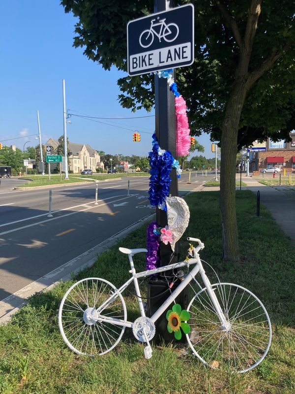 A memorial along Woodward Avenue in Ferndale marks the death of David Ploof, a 33-year-old who died June 18, 2026, when the e-bike he was riding was hit by an Oakland County Road Commission truck near the former Tim Horton's restaurant.