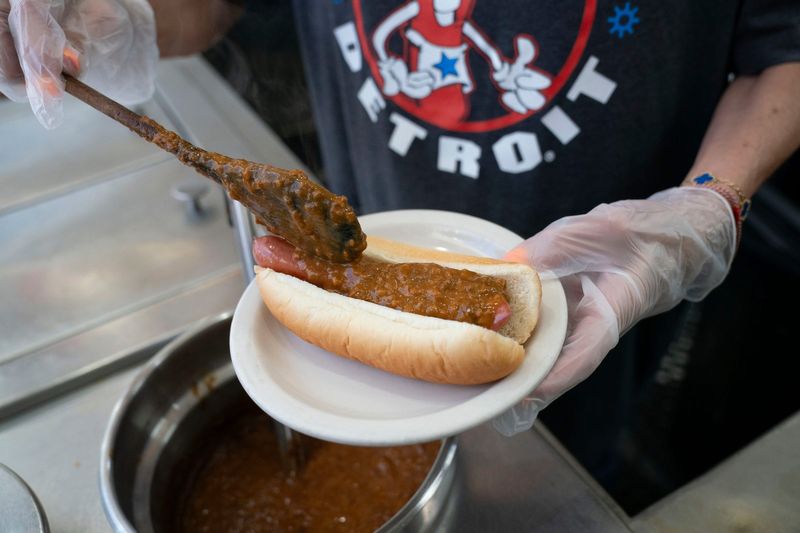 American Coney Island owner Grace Keros tops a hot dog with chili on Wednesday, July 15, 2026.