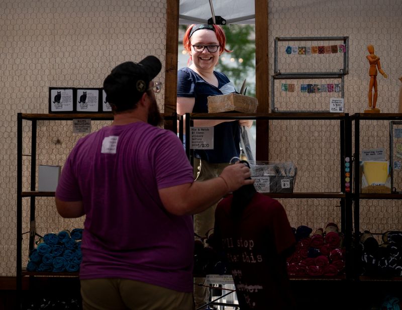 Robert Fontenot, left, 37, of Hammond, Louisiana, talks to Mis Sweetland, 23, of Slidell, Louisiana, as they set up the Be Awesome Read Books tent on E. Liberty St. the day prior to the start of the Ann Arbor Art Fair on Wednesday, July 15, 2026. The art fair runs from July 16 - July 18.