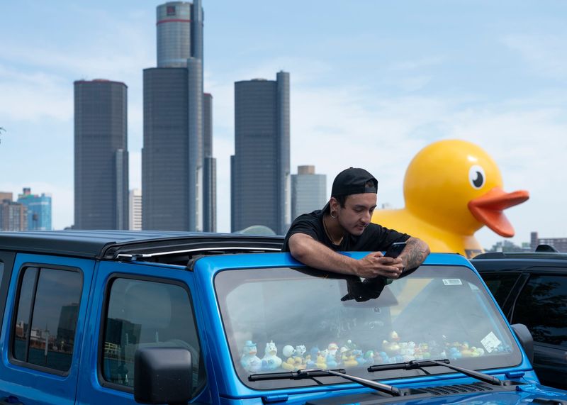 Nicholas DeCiantis, of Windsor, Ontario, 27, checks his phone in his Jeep full of Jeep ducks on the dashboard in Windsor, Ontario on Wednesday, July 15, 2026.