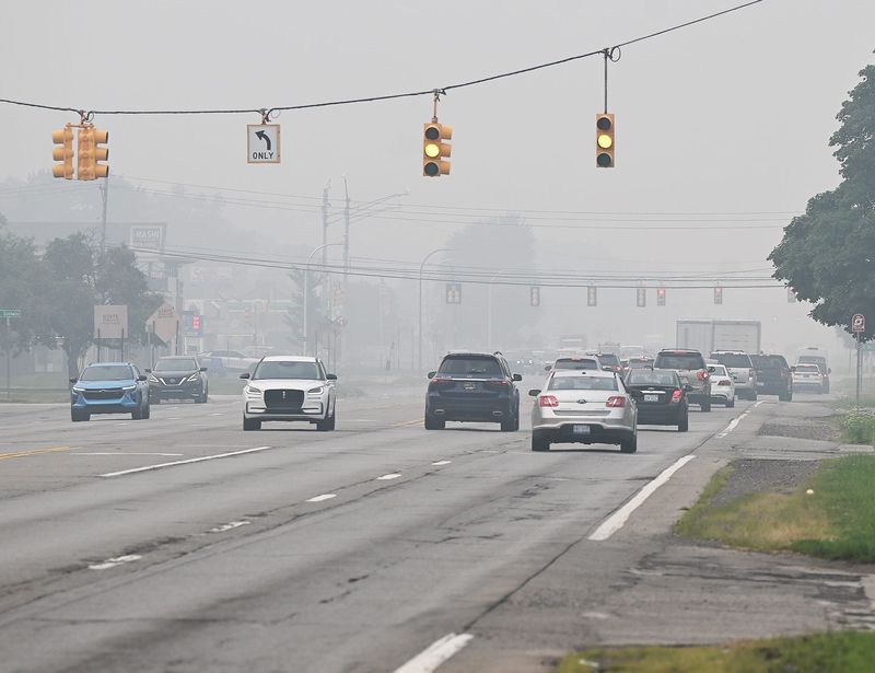 Cars travel southbound on Southfield Rd. as the smoke from the wildfire lingers in the background on Thursday, July 16, 2026, in Oak Park, MI.