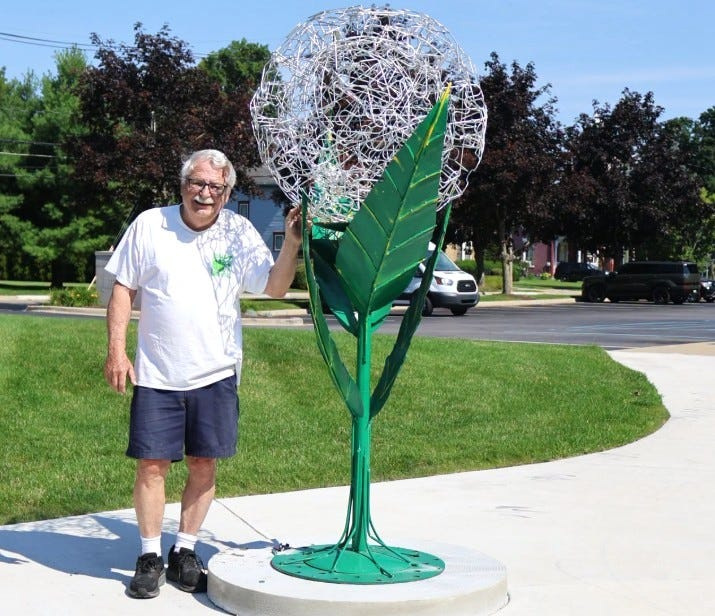 Fremont, Indiana sculptor Greg Summers next to his recycled metal dandelion outside Coldwater's Brown Municipal Building.