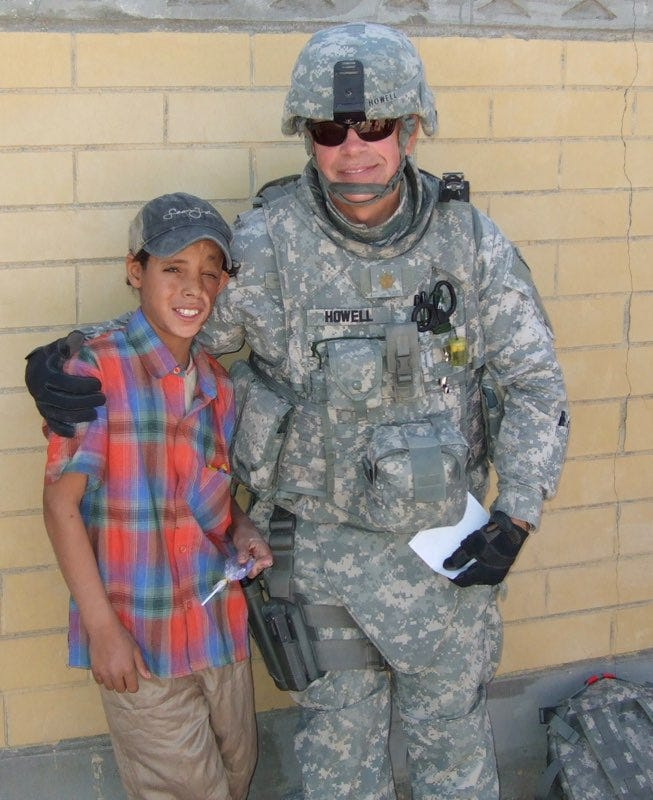 David Howell, then a major in the Michigan Army National Guard, is pictured with Mohammed, then 11 or 12, in Iraq.