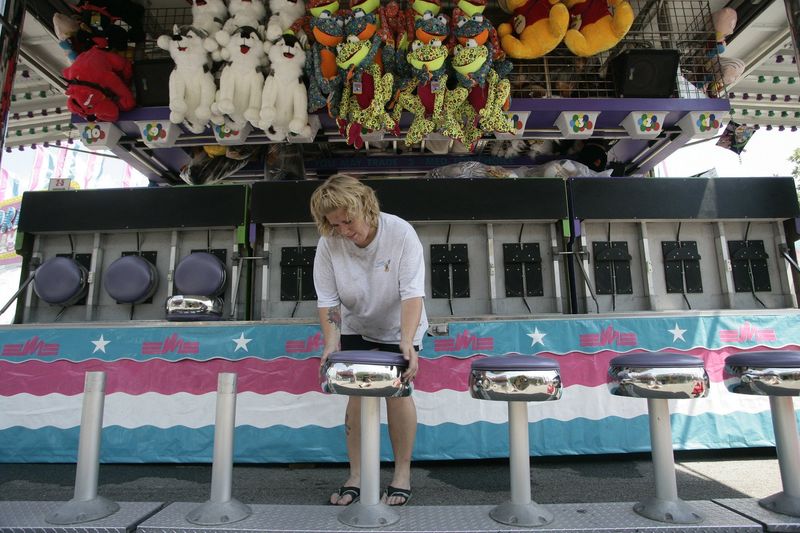 Dawn Ramashka of Ocean City, Maryland, puts the seats on the stands while she is setting up the balloon racer game on Aug. 2, 2006 during the setup for Sterlingfest 2006 Art and Jazz Fair