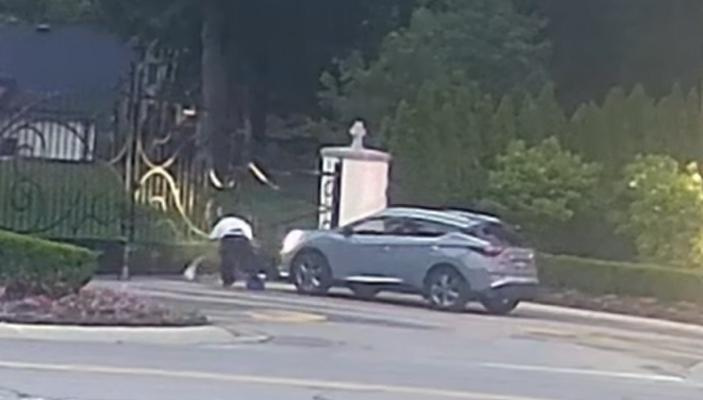 A screenshot from a video released by Southfield Police shows a man dropping what appears to be a small sack at the gates of Holy Sepulchre Cemetery in Southfield.