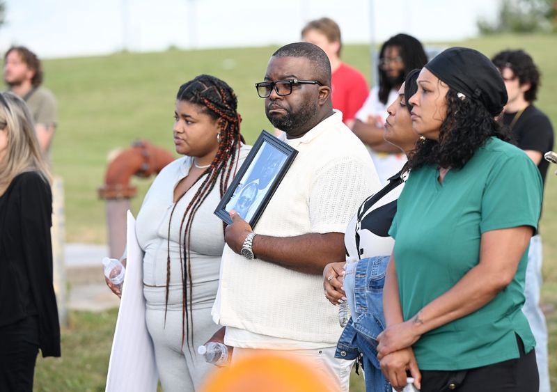 Don Howard holds a photo of himself and his daughter, Khaira Howard who died in a medical observation cell at WomenÕs Huron Valley Correctional Facility, during a vigil for inmates who died while serving time at WomenÕs Huron Valley Correctional Facility on July 22, 2026 in Pittsfield Township, Mich. KhairaÕs mother, Shaquillia DeShields directly to right of Howard, with DeShieldÕs cousin, Jody Branham, right, and at far left is KhairaÕs sister, Kanisha Howard.