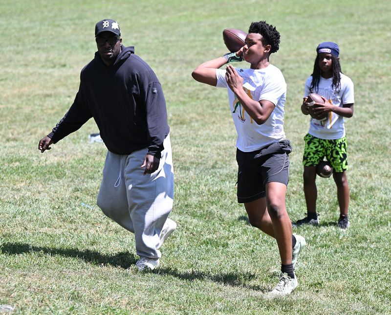 Austin Mitchell of Harper Woods (r), makes a pass during a drill under the watchful eye of Devin Gardner at his mentorship program “Young Go Getters,” which teaches quarterback skills to Detroit-area kids on Thursday, July 23, 2026, at Shepherd Park in Oak Park, MI.