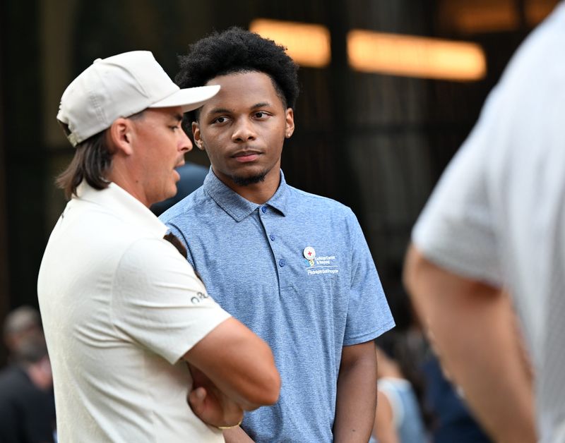 Elijah Robinson, 17, of Sterling Heights, right, talks with pro golfer and his partner for the event Rickie Fowler during Par 3 in the D on July 28, 2026 in Detroit. Six golfers from the Rocket Classic participated in teeing off from five stories atop the Traver | UBS building at 1217 Woodward Avenue to a green located across Woodward Avenue created next to the Hudson’s Detroit building.